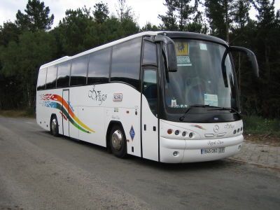 Un autobús blanco está estacionado al costado de la carretera.
