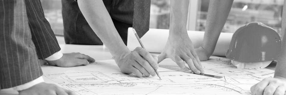 Persone che esaminano progetti, discutono di un progetto. Un casco è sul tavolo, vicino ai progetti arrotolati.