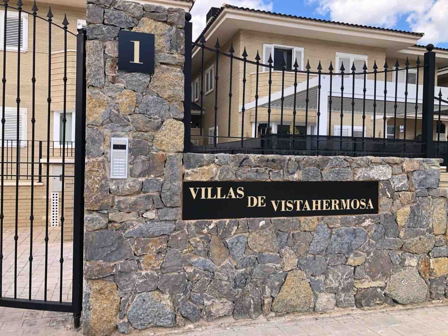 La entrada a Villas de Vistahermosa, con su pilar de piedra y valla metálica, luce un cartel negro con letras doradas y el número 1.