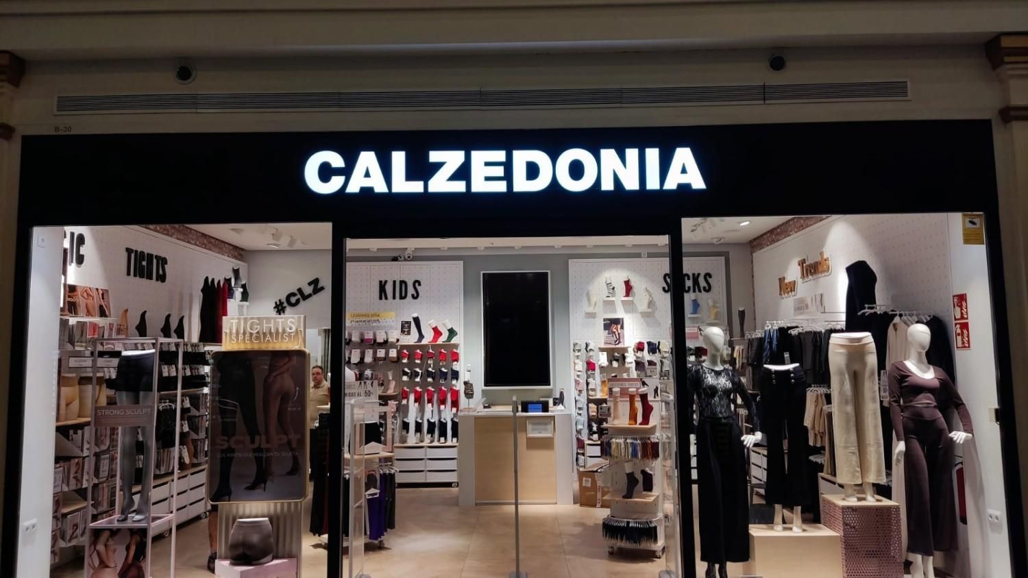 Fachada de una tienda Calzedonia con letrero de la marca, que muestra estantes con medias y maniquíes en el interior.