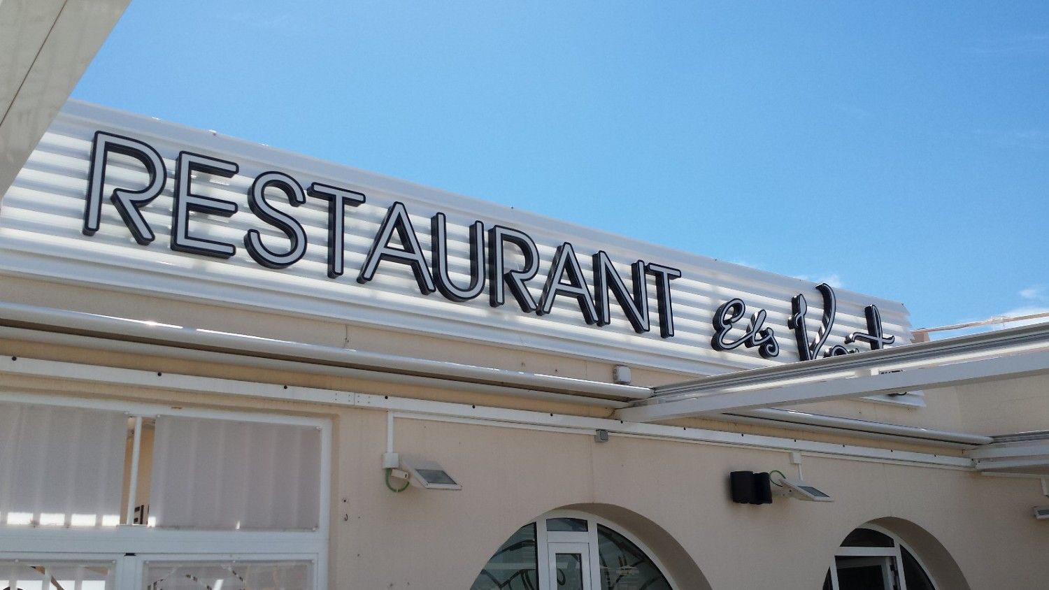 El exterior de un restaurante de color crema con un letrero prominente que dice 