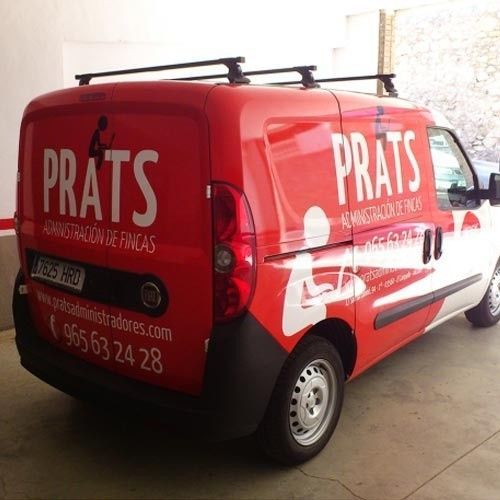 Una furgoneta de servicio roja con el logotipo blanco y la información de contacto de Prats Administración de Fincas estaba estacionada en el interior.