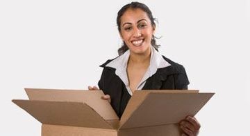 Mujer sonriente sosteniendo cajas de cartón abiertas sobre un fondo blanco.