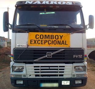 Un camión Volvo FH12 blanco, visto de frente, con un letrero amarillo que dice 