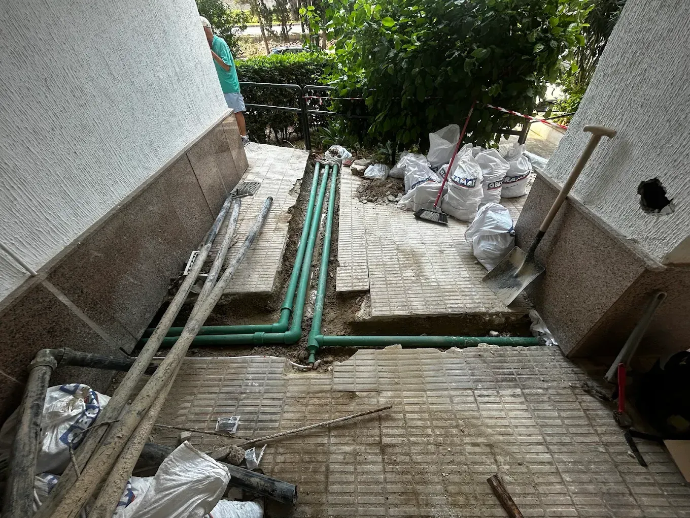 Obra en construcción con tuberías verdes expuestas en una zanja