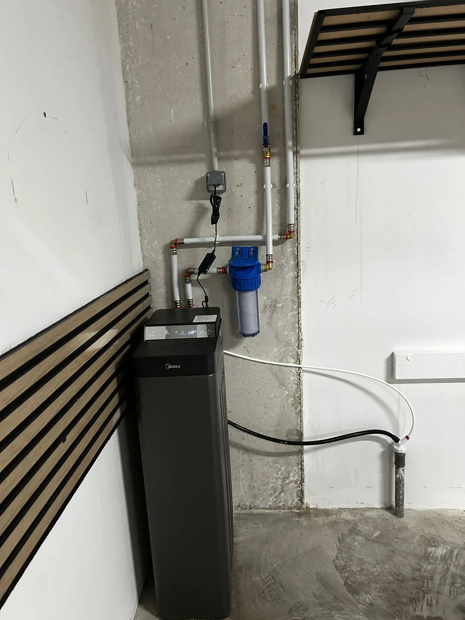 Sistema ablandador de agua instalado contra una pared de hormigón