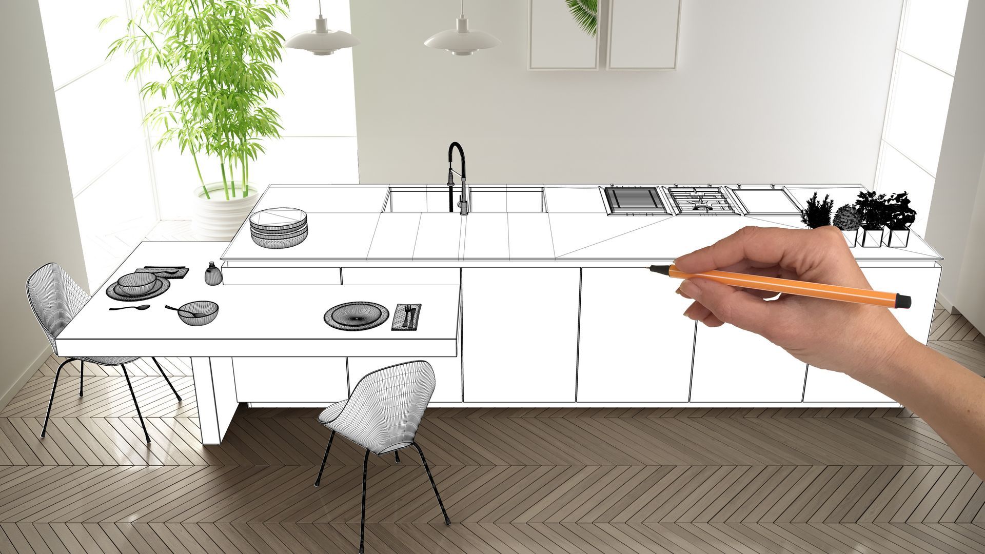 Eine Hand hält einen Bleistift und skizziert eine moderne Küchengestaltung mit Kochinsel, Stühlen und Küchengeräten auf Holzboden.