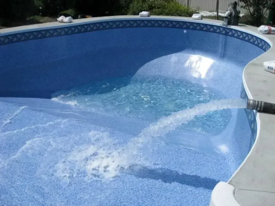 Piscina azul siendo limpiada con agua fluyendo por el fondo.
