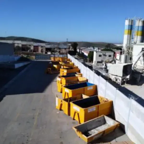Contenedores industriales amarillos alineados en una azotea junto a una pared blanca bajo un cielo azul despejado.