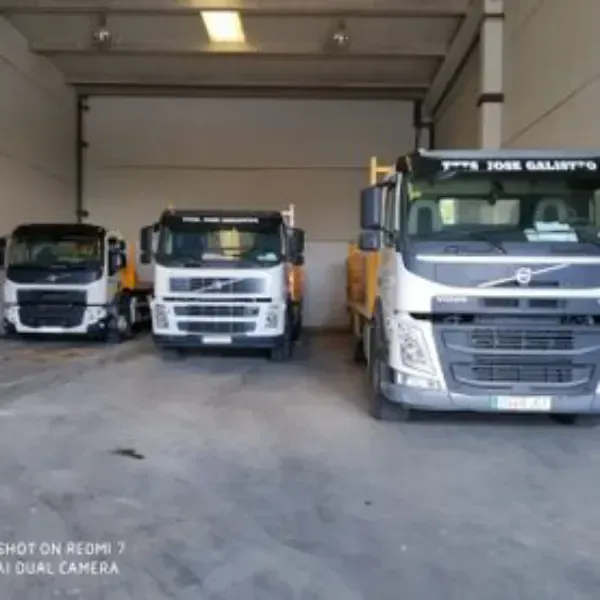 Tres camiones blancos estacionados dentro del garaje de un almacén.