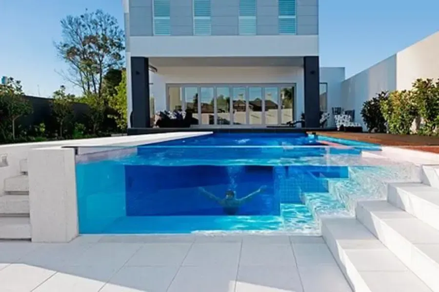 Casa moderna con piscina azul y escalones blancos en la entrada.