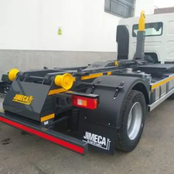 Remolque de plataforma plana JimecaT amarillo y negro con enganche trasero en un garaje interior.