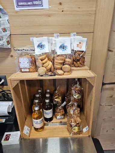 Présentoir en caisses de bois contenant des biscuits emballés et des liquides en bouteille contre un mur lambrissé de bois.