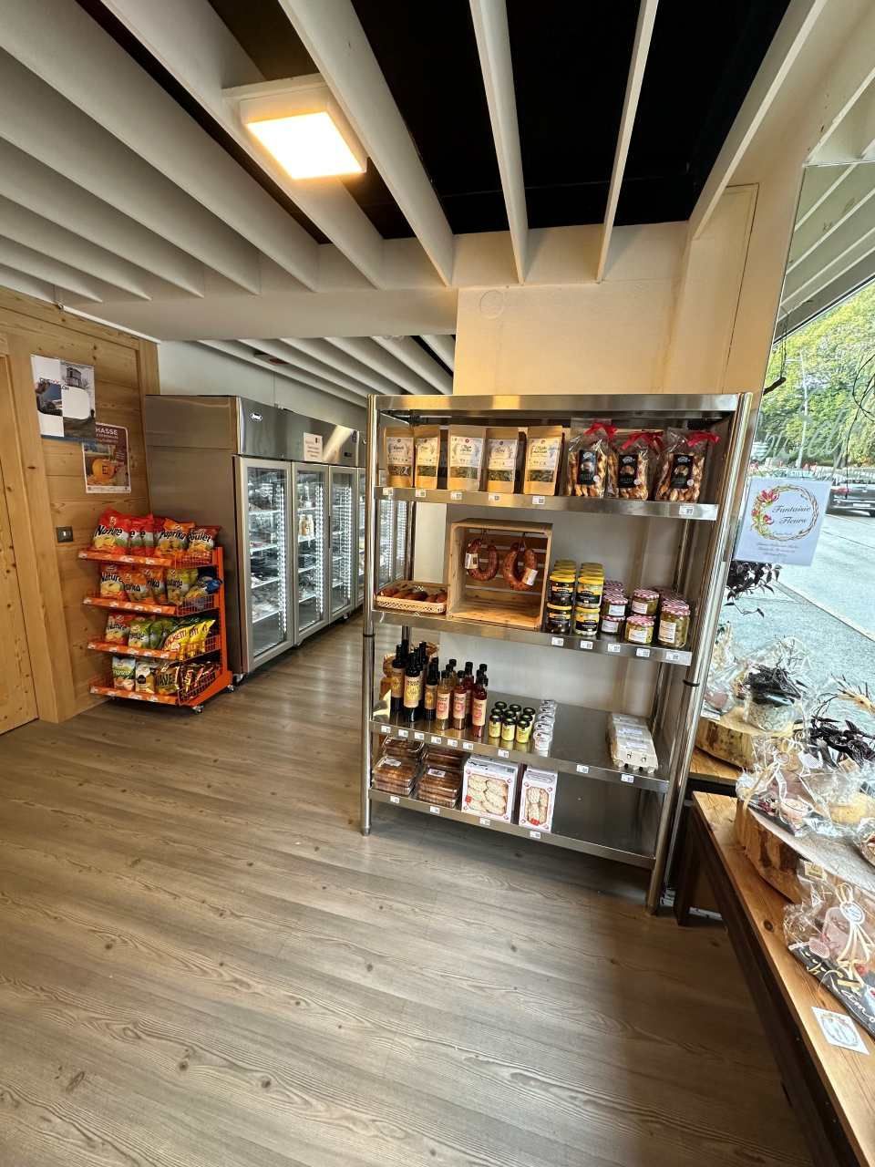 Intérieur d'un magasin avec des étagères de produits alimentaires, un réfrigérateur et un plafond en bois.