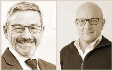 Auf einem Schwarzweißfoto lächelt ein Mann mit Bart und Brille.