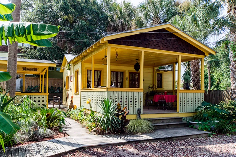 A small yellow house with a porch and a table