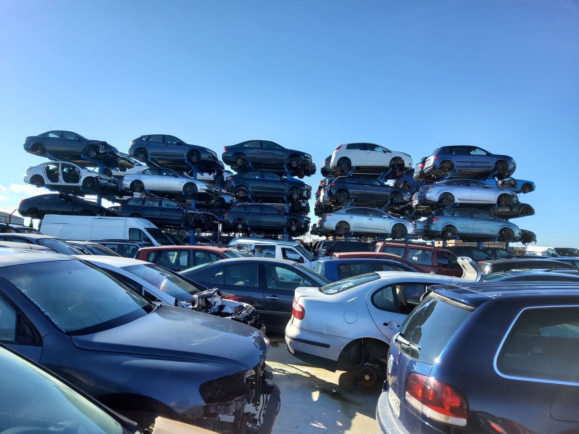 Hay muchos coches apilados uno encima del otro en un estacionamiento.