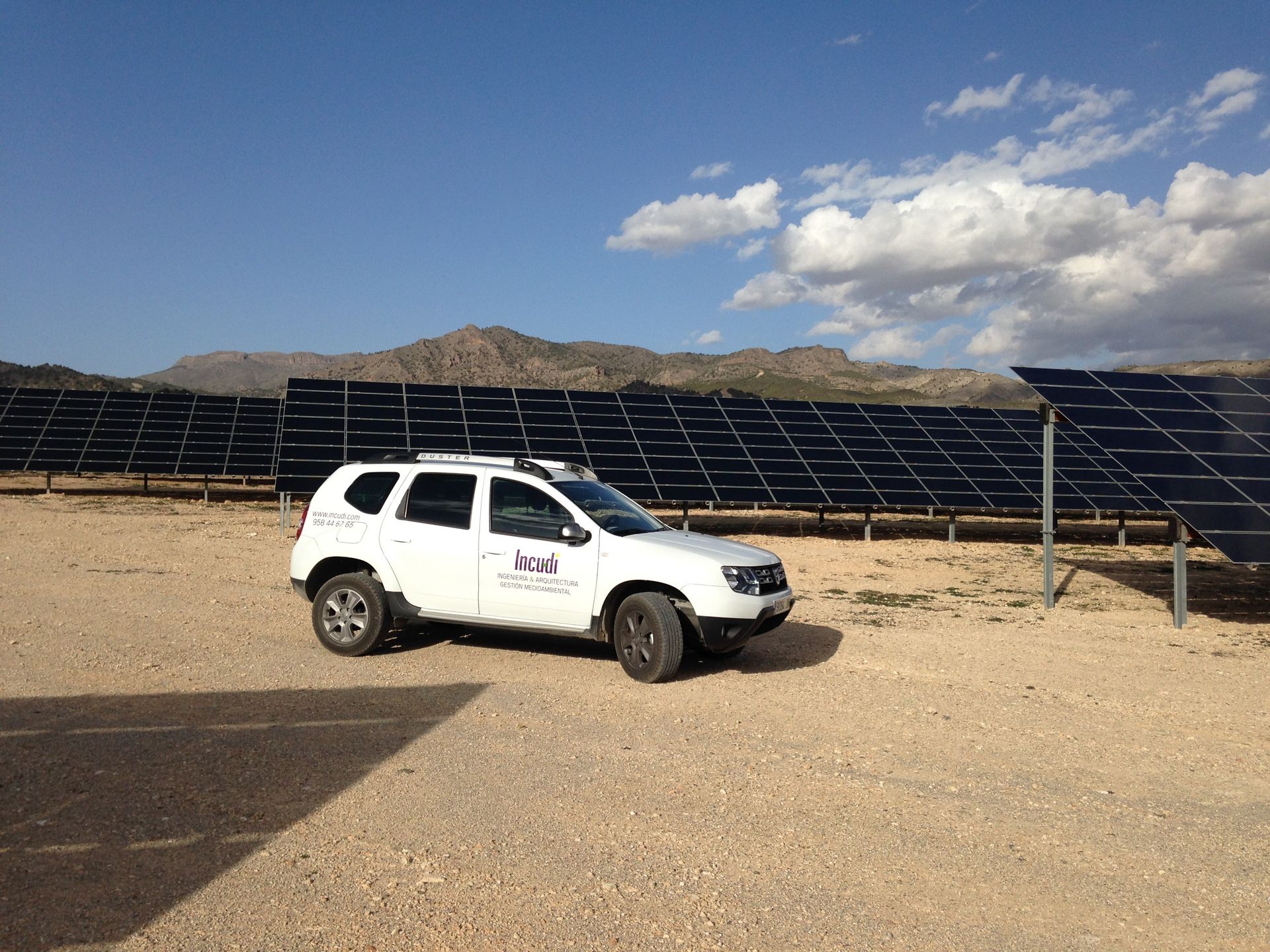 Un todoterreno blanco está estacionado frente a una fila de paneles solares.