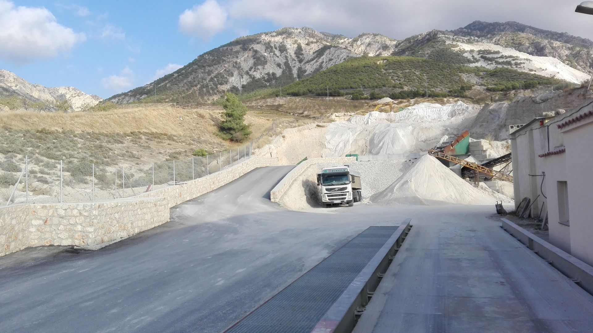 Un camión circula por una carretera con montañas al fondo.
