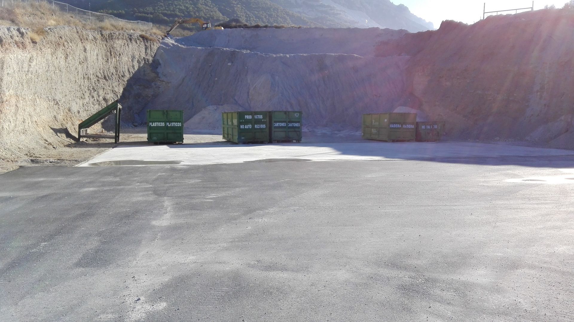 Una fila de contenedores de basura están alineados al costado de una carretera