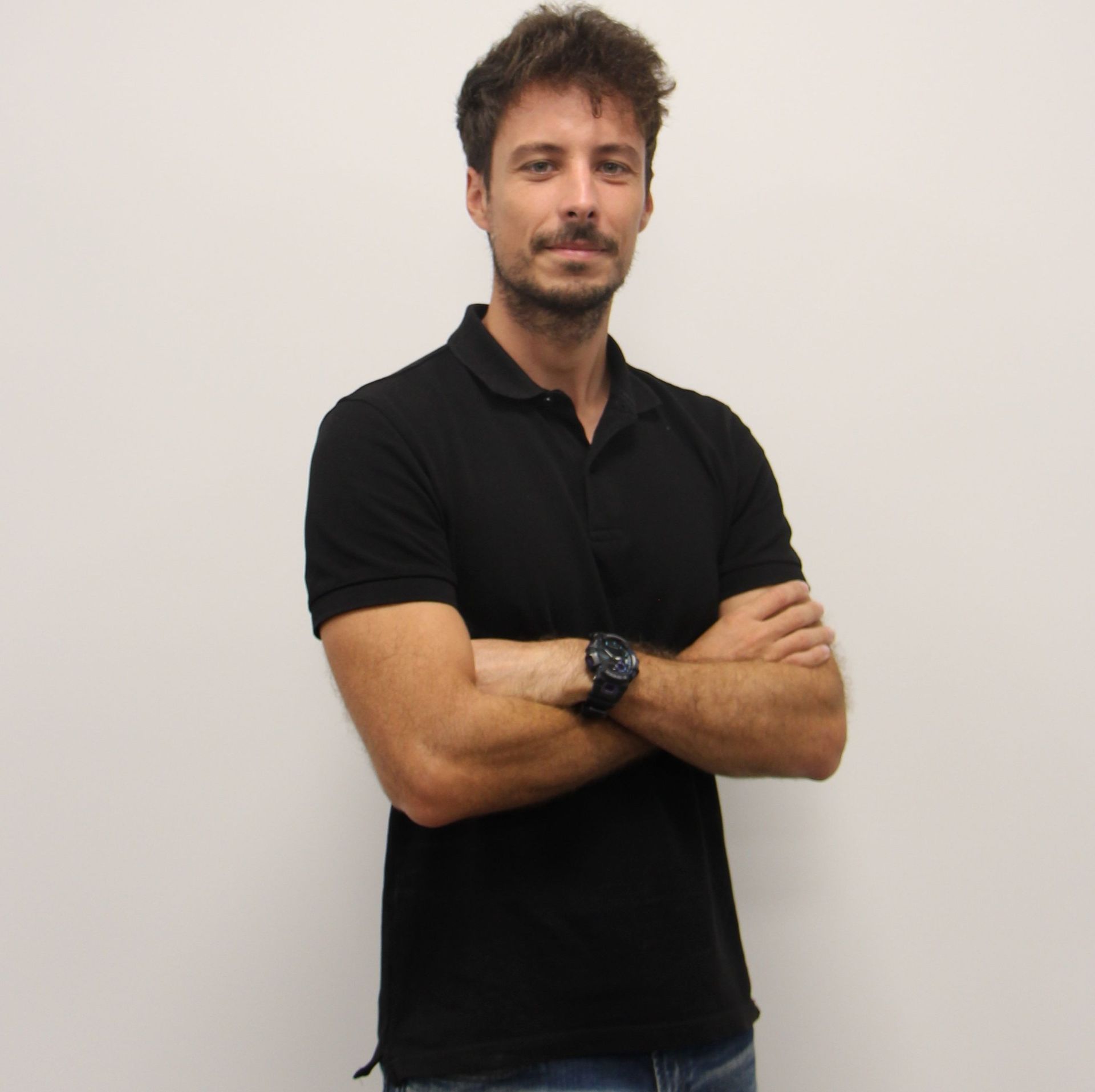 Un hombre con los brazos cruzados y un reloj en la mano.