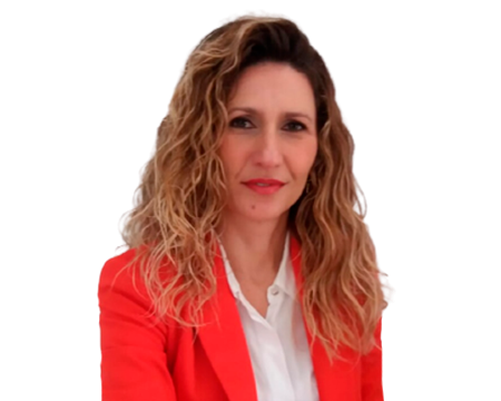 Mujer con cabello rubio rizado, vestida con una camisa blanca y un blazer rojo, sonriendo, sobre un fondo blanco.