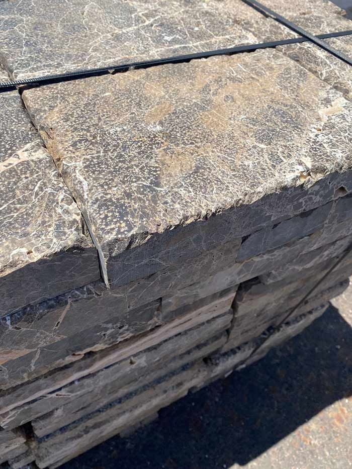 Pila de adoquines de piedra rectangulares de color gris oscuro.