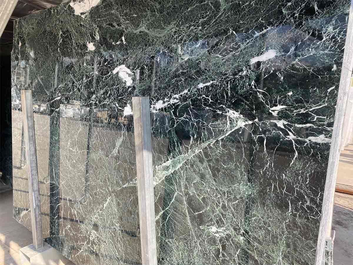 Losas de mármol verde con vetas blancas. Apoyadas sobre soportes, en un entorno exterior.