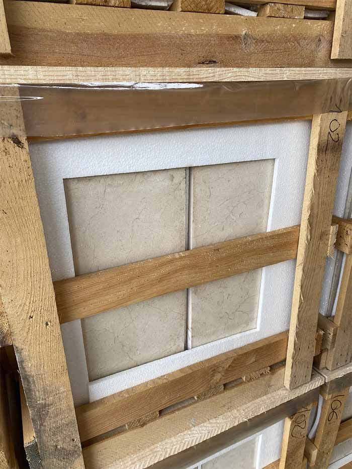 Cuatro baldosas de color beige protegidas dentro de una caja de madera.