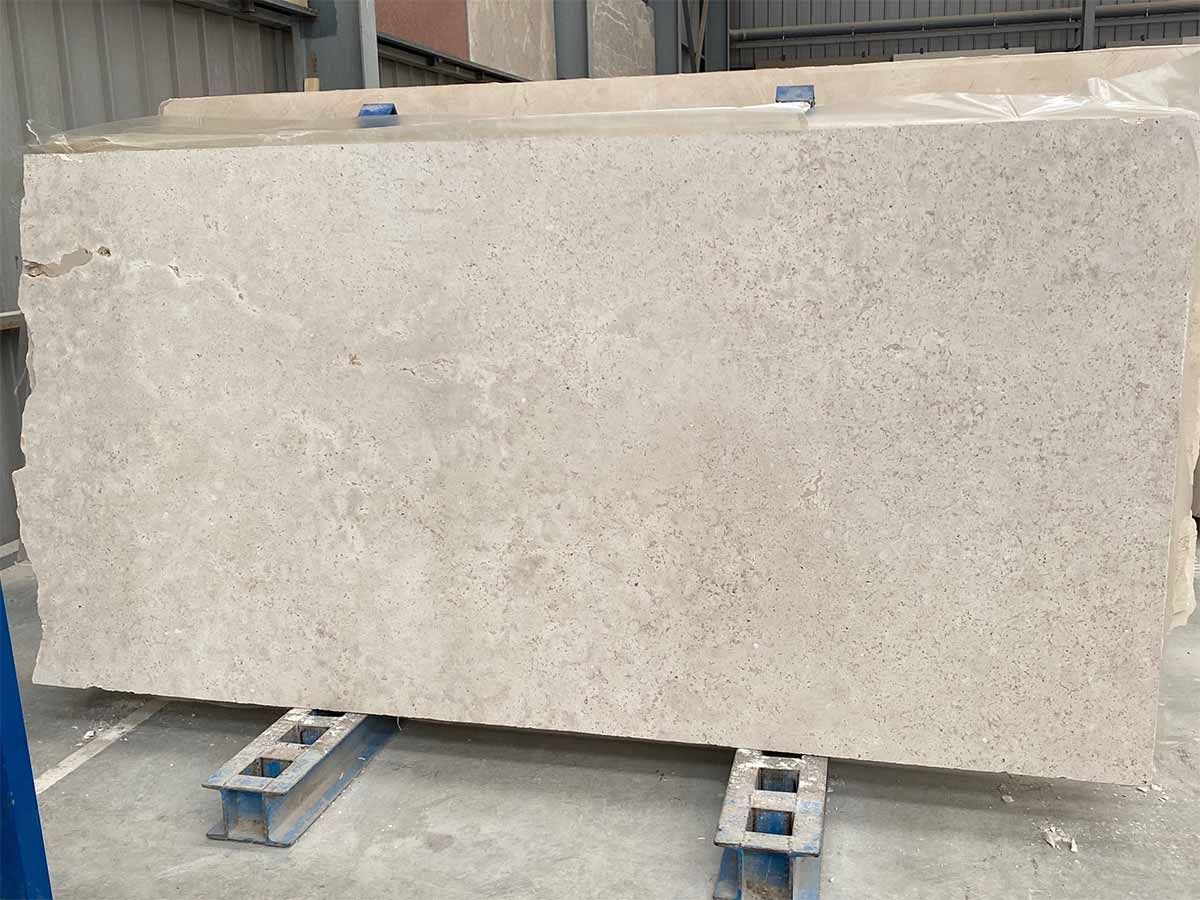 Gran losa de piedra de color beige claro sobre estructura metálica de soporte, posiblemente para encimeras.