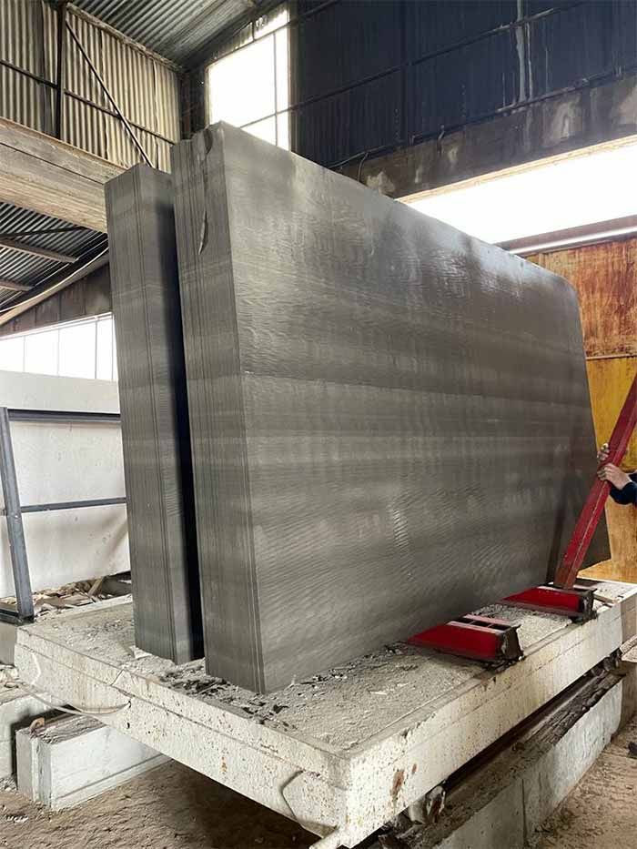 Grandes paneles de hormigón, apilados sobre una plataforma, en un entorno industrial.