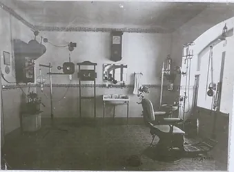 Consultorio dental antiguo, con equipos como silla, lavabo y máquina de rayos X.