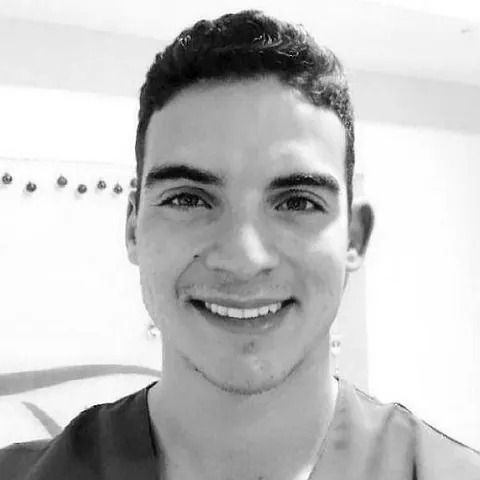 Joven sonriente con cabello oscuro, en escala de grises.