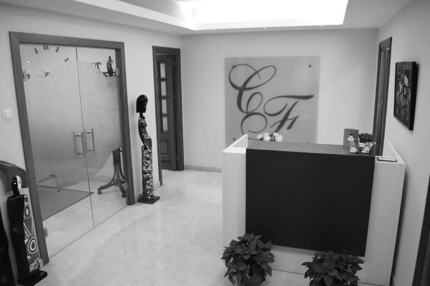 Área de recepción con un gran logotipo, un mostrador de recepción y una puerta de vidrio.