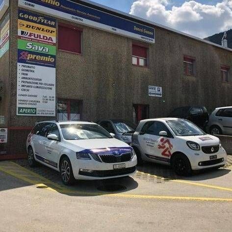 Due auto parcheggiate davanti a un edificio commerciale con insegne di pneumatici Goodyear, Dunlop, Fulda e Sava.