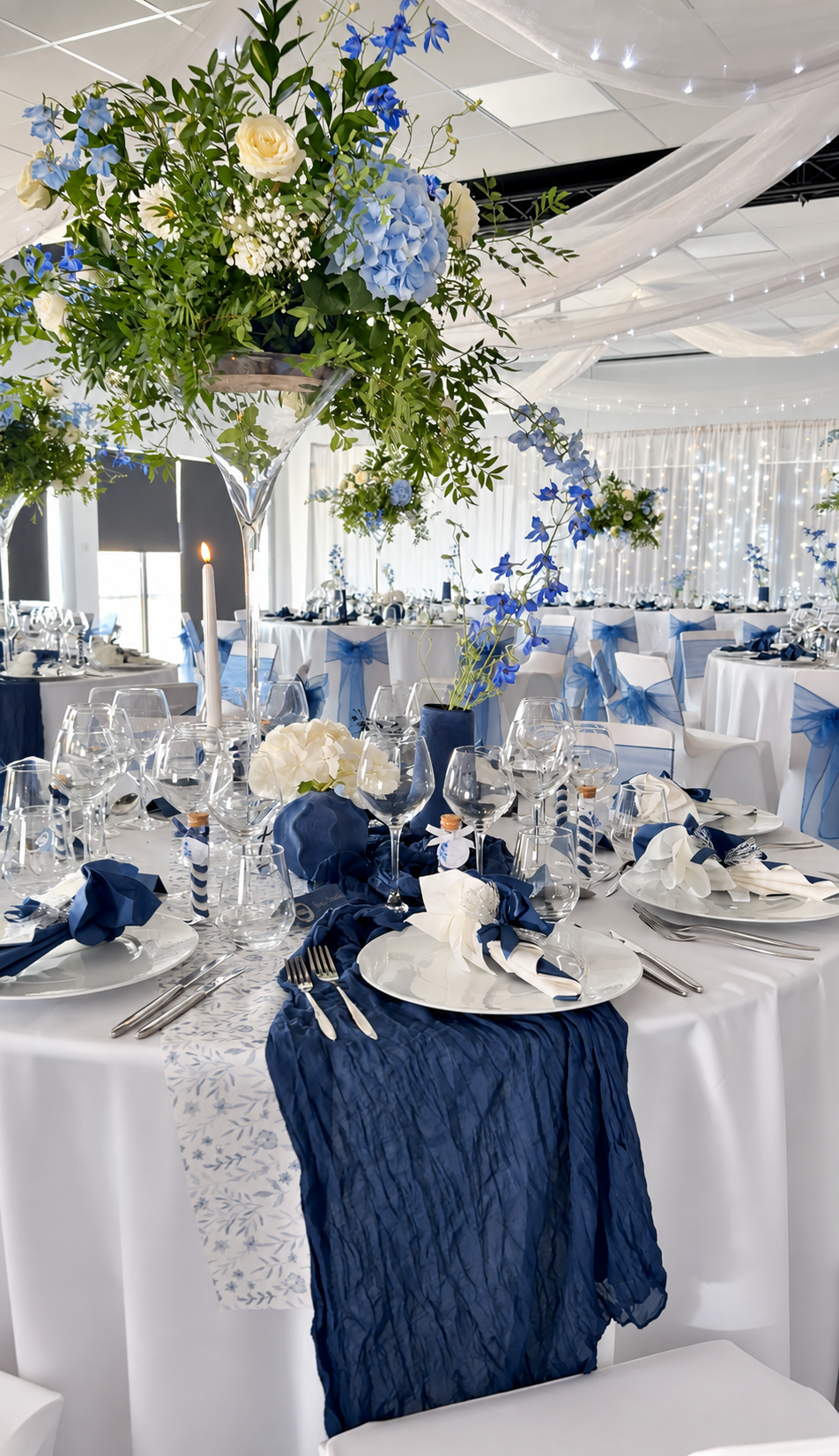 Élégante table de banquet décorée de blanc et de bleu marine, avec un grand centre de table floral.