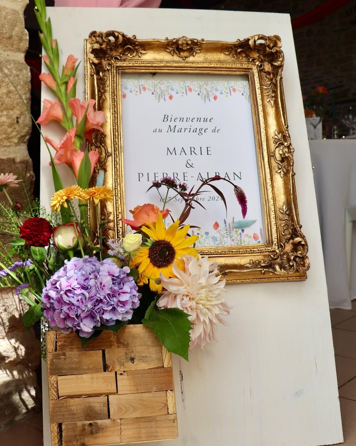 Un cadre doré, décoré de fleurs, qui présente le mariage d'un couple.