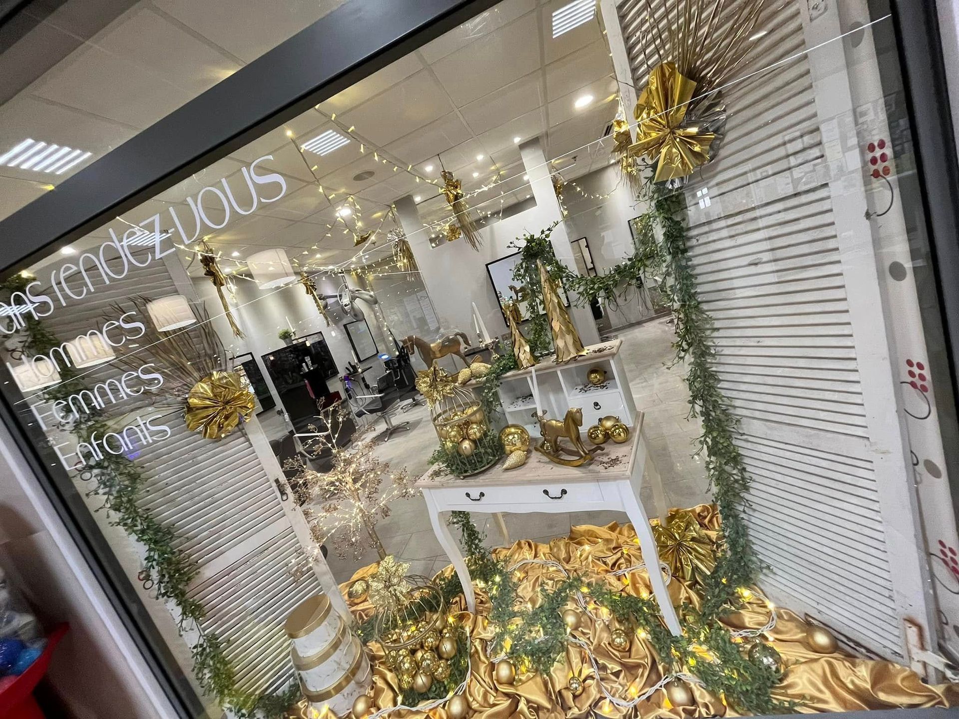 Vitrine d'un salon de coiffure décorée pour les fêtes de fin d'année dans des tons de doré.