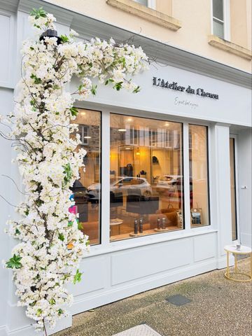 Devanture d'un salon de coiffure décorée de fleurs blanches.
