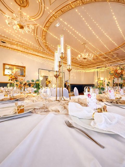 Élégante salle de réception avec un plafond doré illuminé par des lustres et des guirlandes.