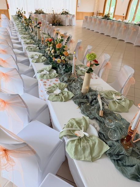 Table de banquet avec des décorations florales dans des tons de vert et d’orange.