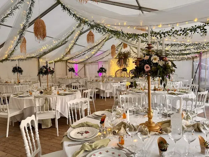 Réception élégante sous une tente blanche avec des tables rondes décorées.