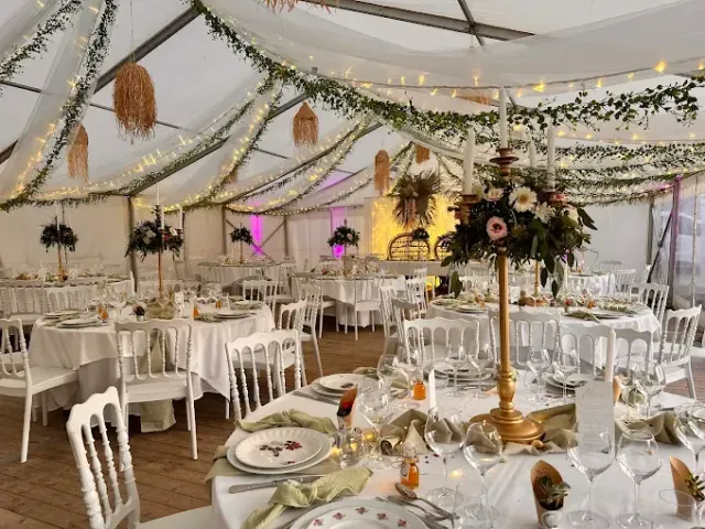 Réception élégante sous une tente blanche avec des tables rondes décorées.