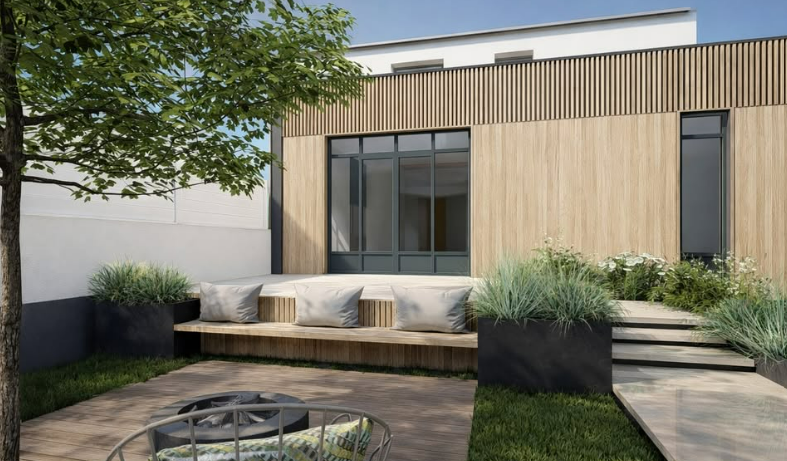 Terrasse moderne dans un jardin avec un grand siège et des coussins, des plantes en pot et une allée de dalles à côté d'une maison.