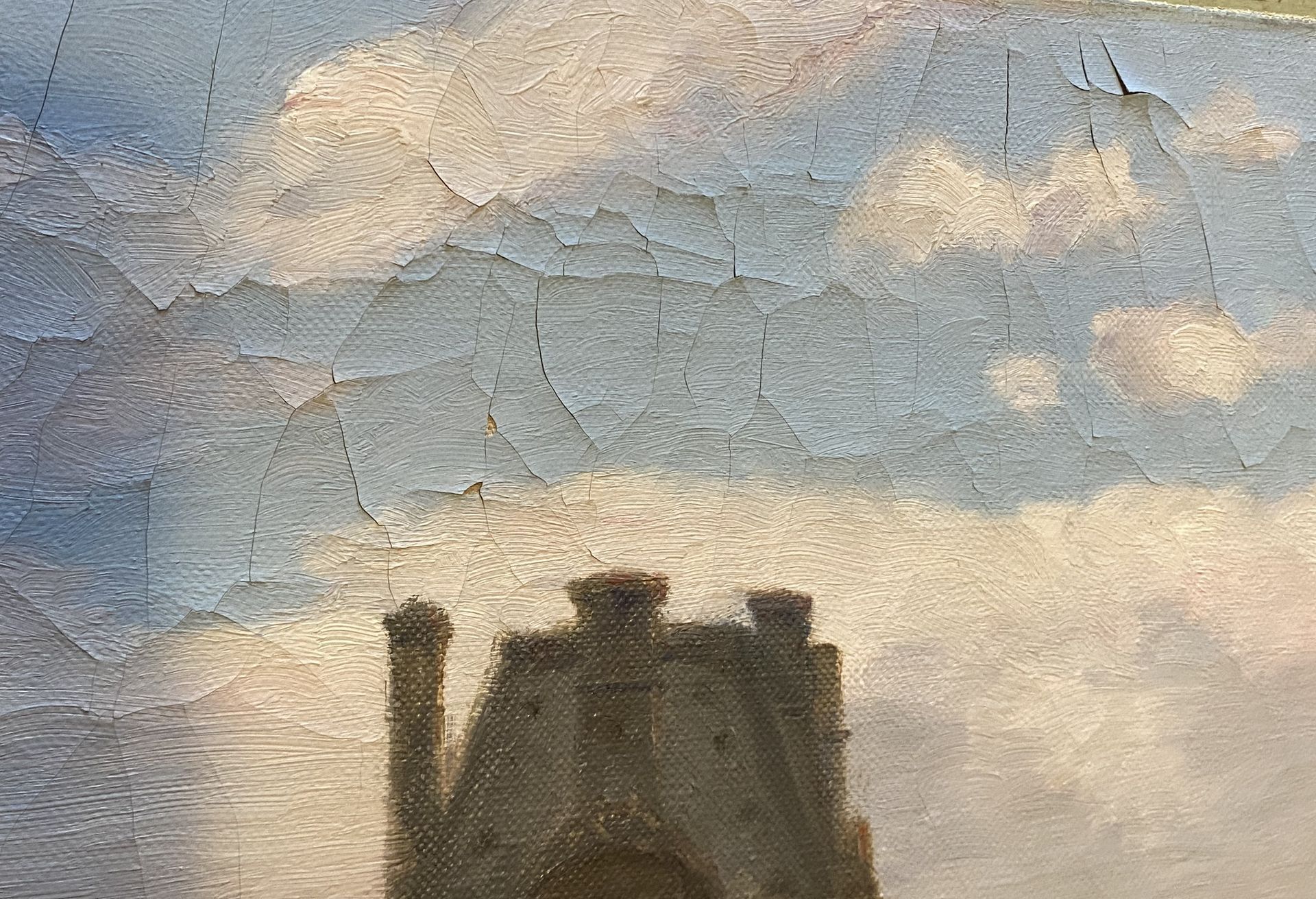 Haut d'un bâtiment peint sous un ciel bleu avec des nuages blancs dont la peinture s'écaille