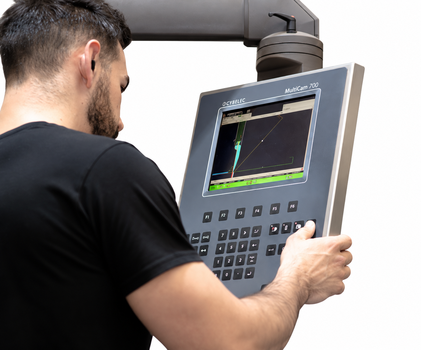 Técnico manejando un gran panel de control industrial gris con pantalla y teclado numérico