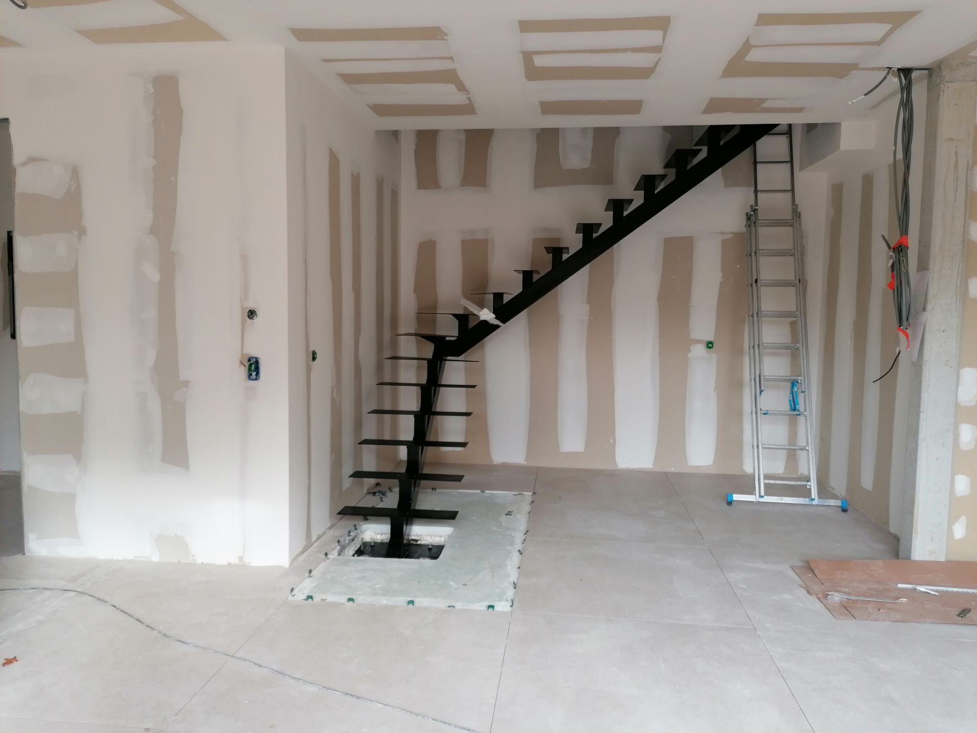 Photo d'escaliers en métal noirs dans une pièce en travaux