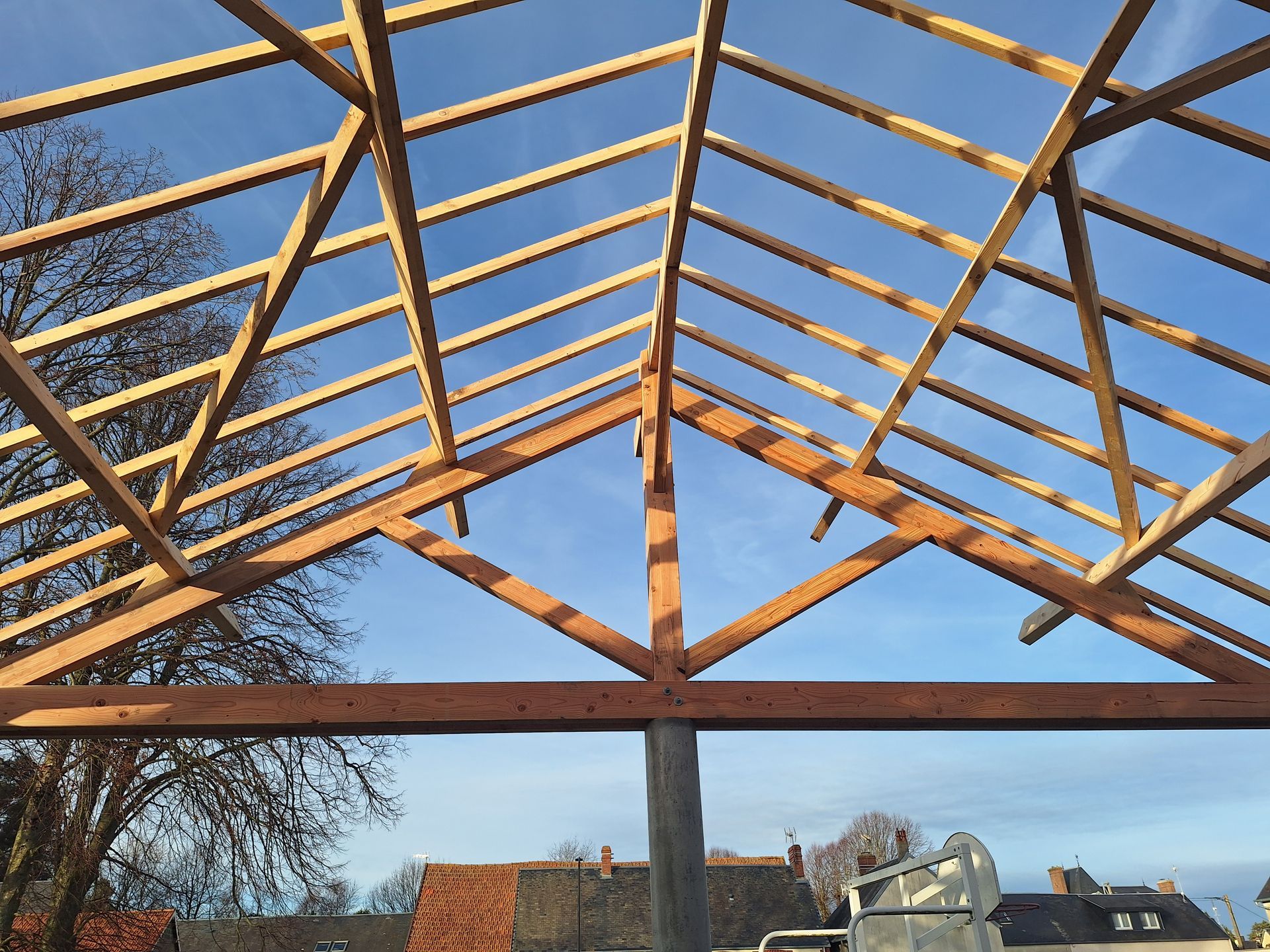 Charpente en bois sur fond de ciel bleu, révélant le chantier de construction d'un bâtiment.
