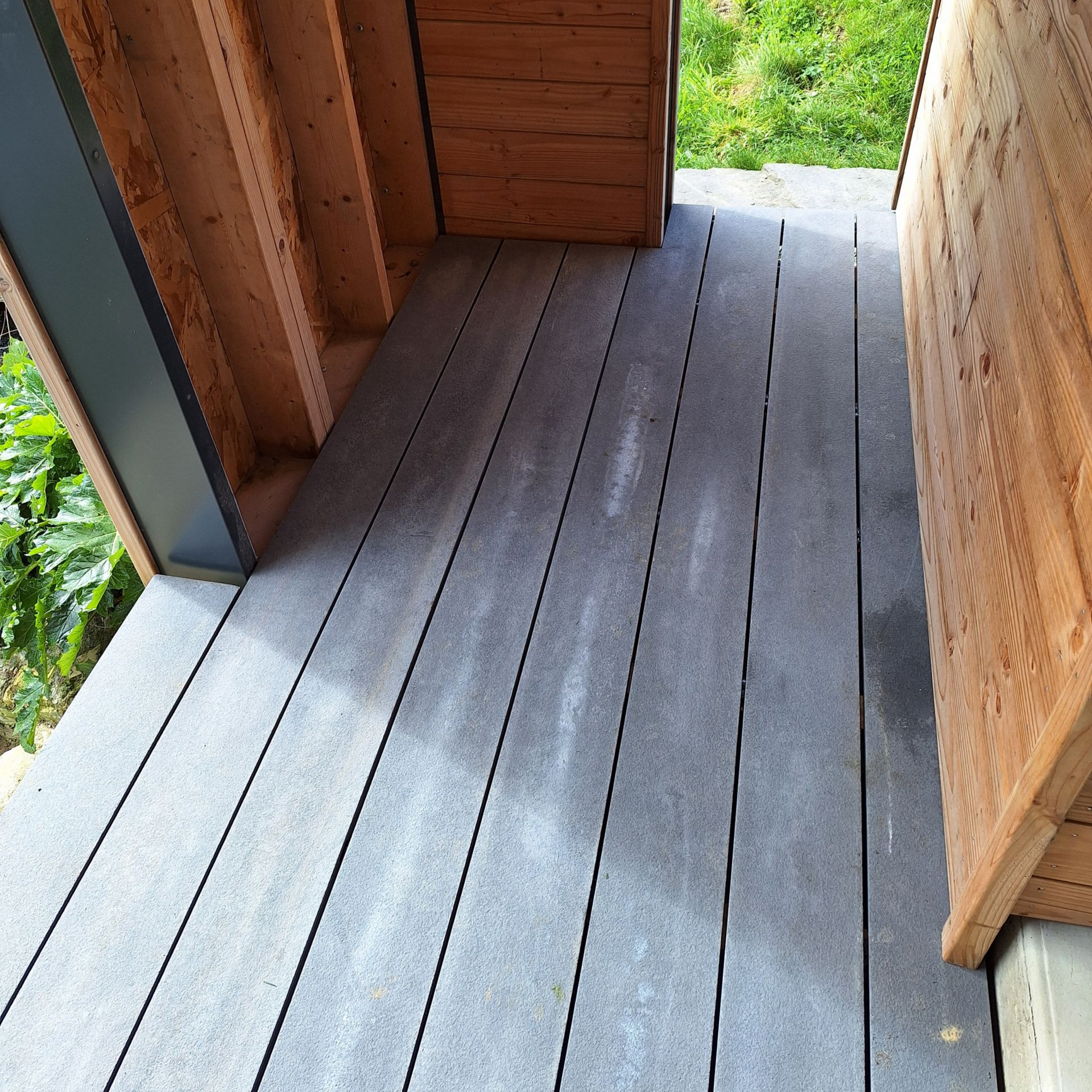 Terrasse composite grise entre structures en bois.