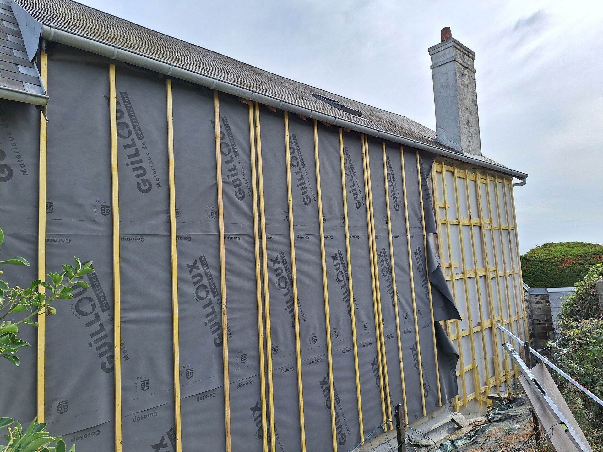 Mur extérieur avec montants en bois et isolation noire en cours d'installation sur une maison.